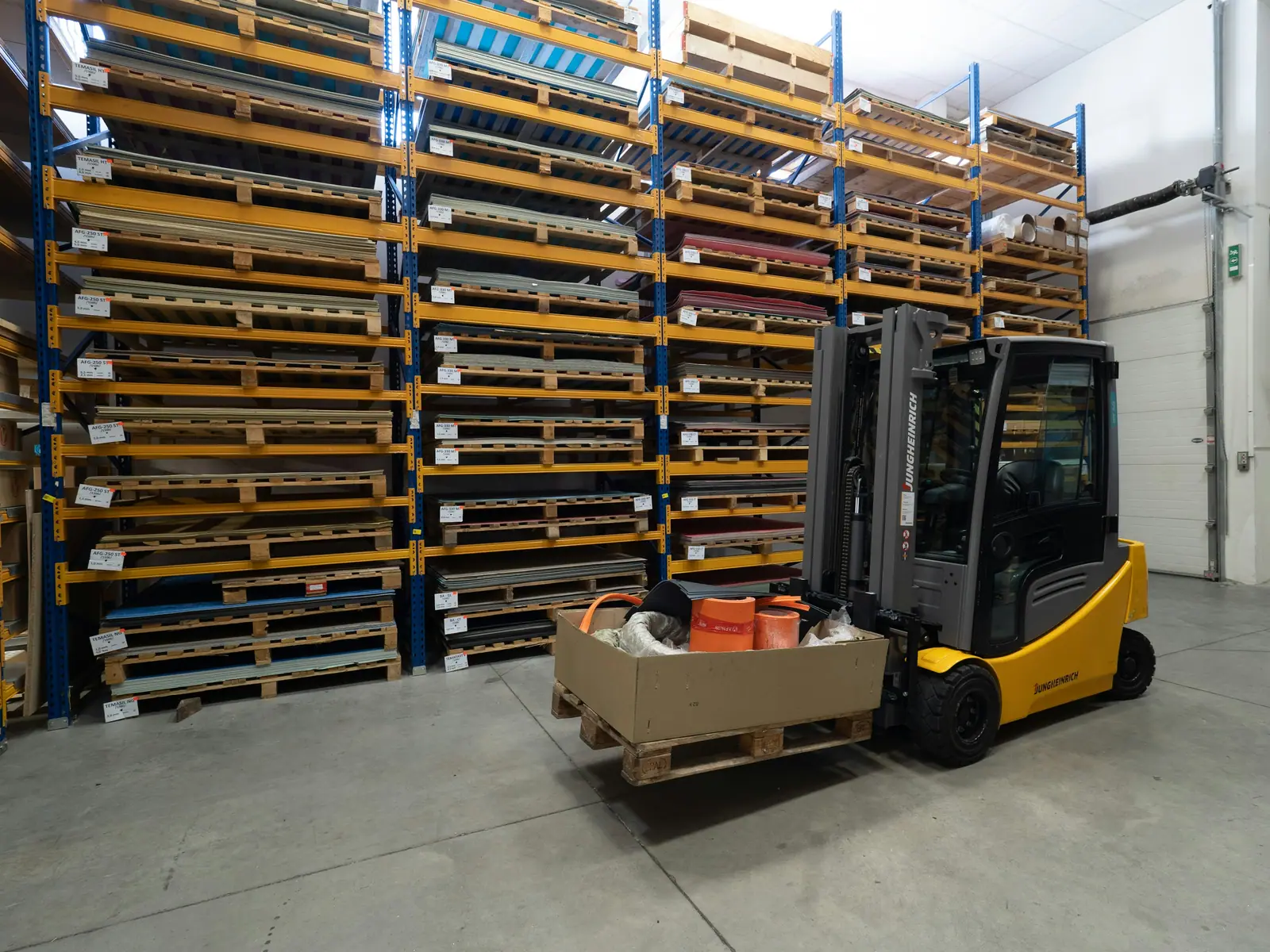 Forklift carrying a palletised load in front of warehouse racking