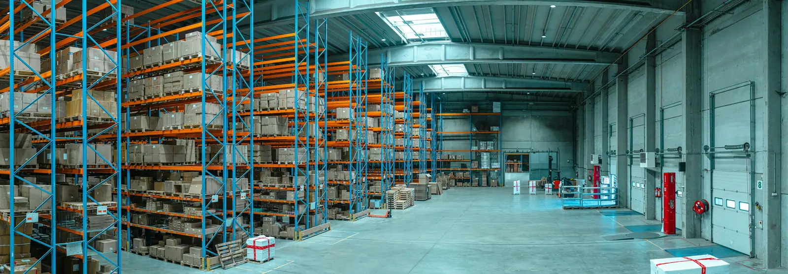 Wide view of a warehouse with tall blue and orange racking holding boxed goods